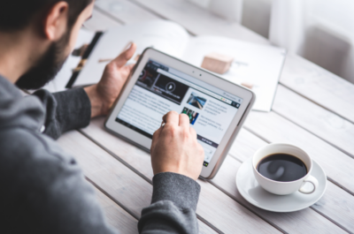 Man holding a tablet scrolling through a website.