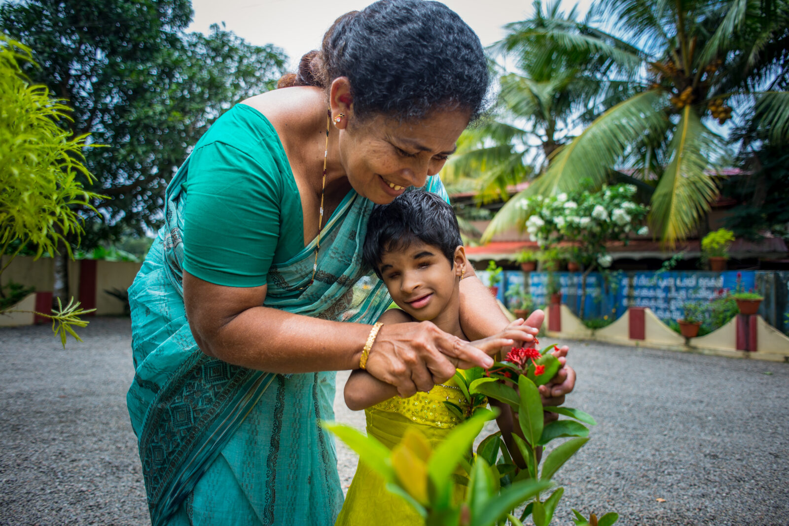 Woman helping a young child to feel and touch a flower.